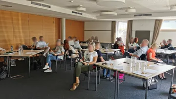 Leute, die in einem Konferenzraum sitzen und sich Notizen machen.
