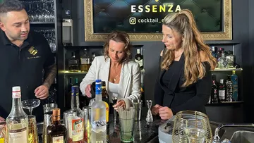 Three people making cocktails at a bar.