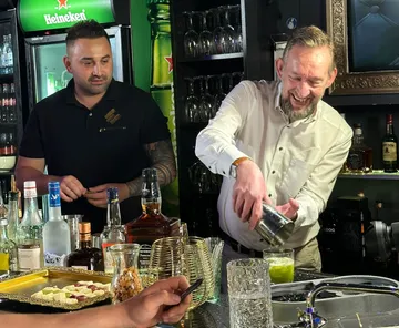 Two bartenders making drinks in a bar.