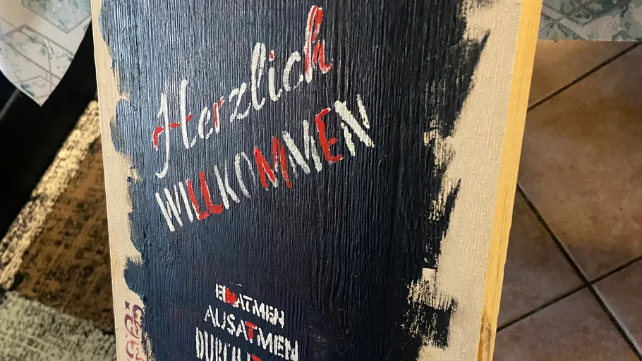Holzschild mit handbemalter Willkommensnachricht.