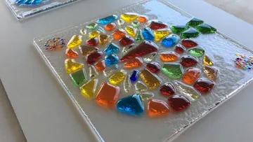 Buntes Glasmosaik auf quadratischer Fliese.