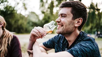 Lächelnder Mann mit Glas, Einstellung im Freien.