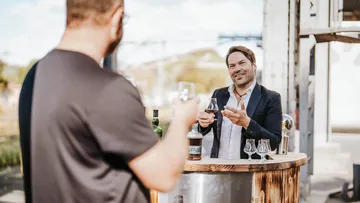 Man offering wine tasting outdoors.