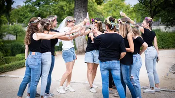 Gruppe von Frauen, die Blumenkronen tragen und im Park tosten.