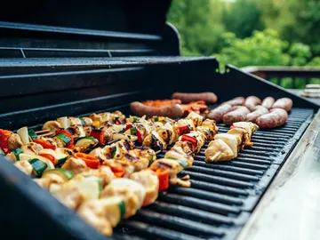 Grill mit Fleisch und Gemüse, der draußen zubereitet wird.