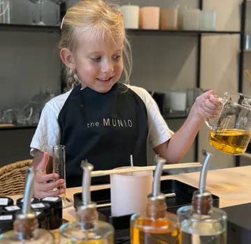 Child making candles with wax in store.