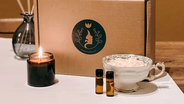 Kerze, ätherische Öle, Teetasse neben Geschenkverpackung.