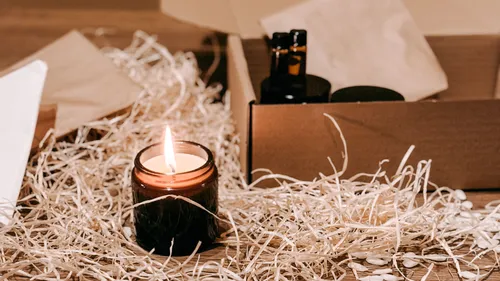 Brennende Kerze auf dem Tisch neben dem Verpackungskarton.