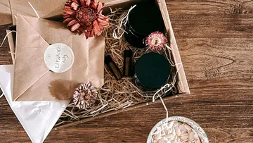 Geschenkbox mit getrockneten Blumen und Gläsern auf dem Tisch.