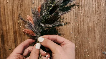 Hände arrangieren getrocknete Blumen auf dem Tisch