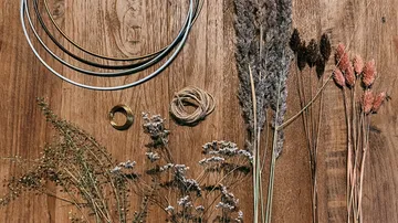 Trockenblumen und Bastelwerkzeuge auf einem Holztisch.