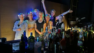 Gruppe von Frauen mit leuchtenden Stirnbändern an der Bar.