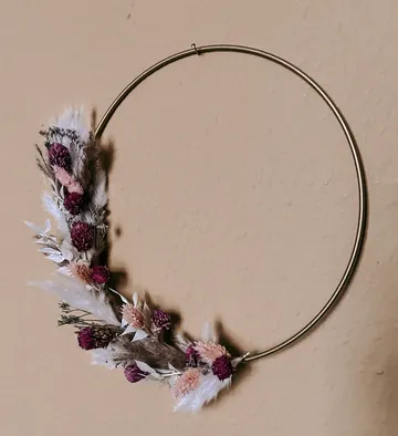 Minimalistischer Blumenkranz auf beiger Wand.