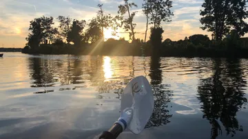 Kajakpaddeln auf einem ruhigen See bei Sonnenuntergang.
