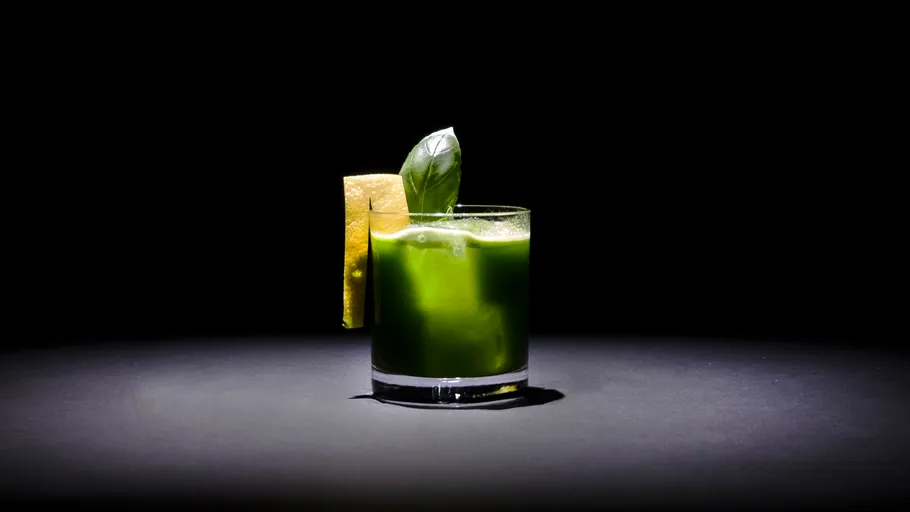 Green cocktail with lemon and mint garnish.