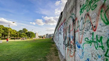 Mit Graffiti bedeckte Berliner Mauer mit grasbewachsenem Park