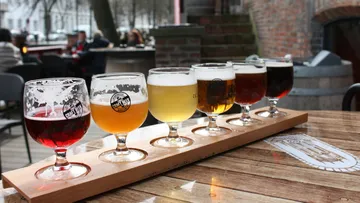 Flight of six craft beers on wooden table.