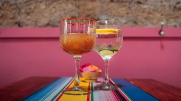 Farbenfrohe Cocktails auf einem bunt gestreiften Tisch.
