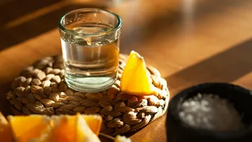 Schnapsglas mit orangefarbenem Keil auf dem Tisch.