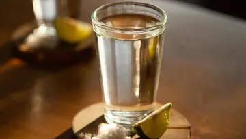 Ein Glas Tequila mit Limettenspalte.