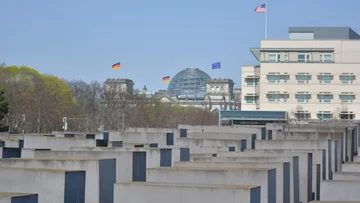 Berlin Holocaust Memorial with Reichstag and flags.