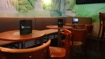 Gemütliches Café mit runden Tischen und Wandgemälden.