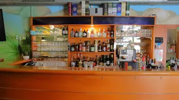 Bar mit Regalen mit verschiedenen Spirituosen und Gläsern.