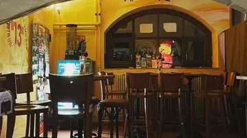 Cozy bar interior with wooden chairs, dim lighting.