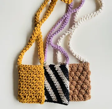 Three crochet bags with braided straps on display.