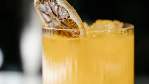 Gelber Cocktail mit Zitronenscheibengarnitur.