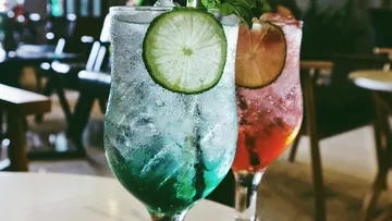 Zwei bunte Cocktails mit Limettenscheiben auf dem Tisch.