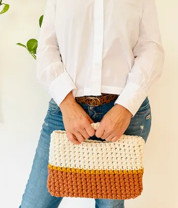Person holding knitted handbag, white shirt and jeans.
