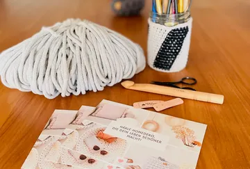 Yarn, tools, and instructions on wooden table.