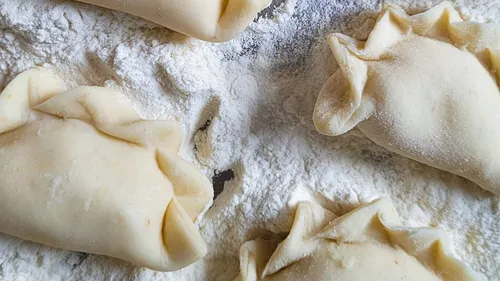 Four uncooked empanadas on floured surface.