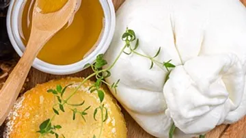 Burrata cheese, honey, bread, herbs on board.