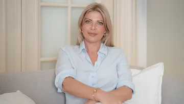 Frau sitzt auf dem Sofa in einem hellen Raum.