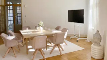 Esszimmer mit Tisch, Stühlen und Fernseher.