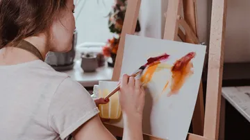 Person painting on canvas at easel.