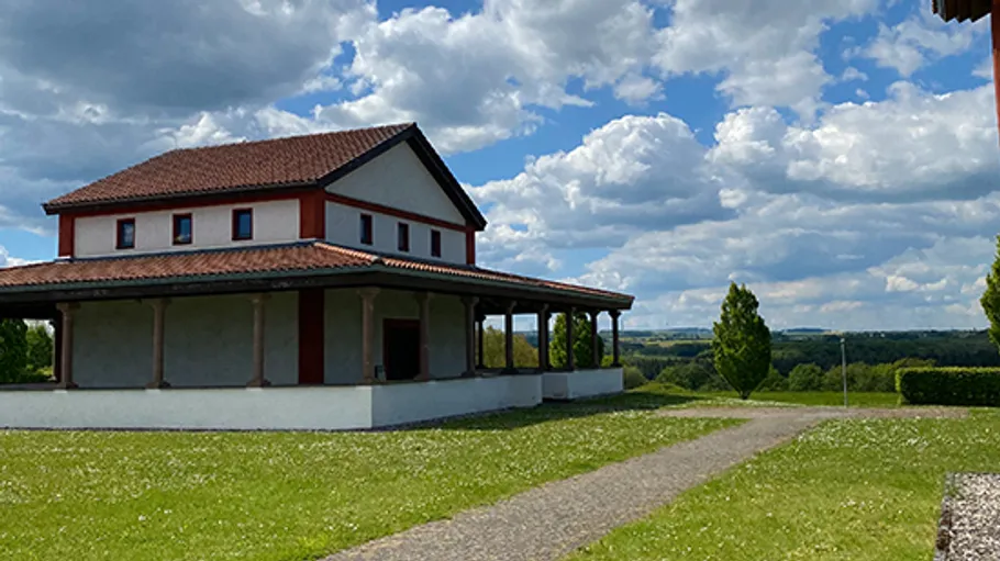 Roman villa reconstruction under blue sky.