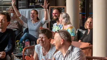 Gruppe von Leuten, die drinnen klatschen und jubeln.