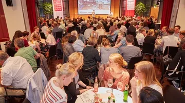 Das Publikum hört dem Moderator im Konferenzraum zu.