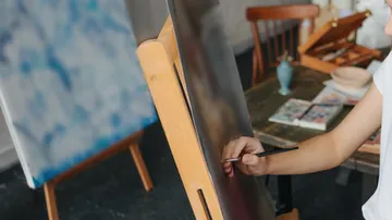 Person painting on canvas in art studio.
