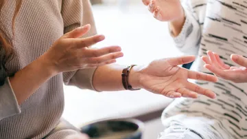 Two people gesturing with hands during conversation.