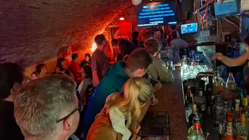 Leute singen Karaoke in einer schwach beleuchteten Bar.