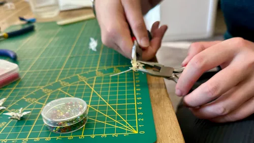 Person, die eine Zange an einem Perlendraht-Projekt benutzt