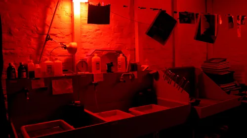 Darkroom with developing trays and hanging photos.