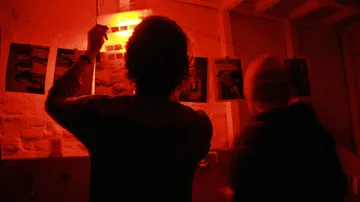 Zwei Personen entwickeln Fotos in der Dunkelkammer.