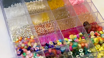Assorted colorful beads in organized plastic container.