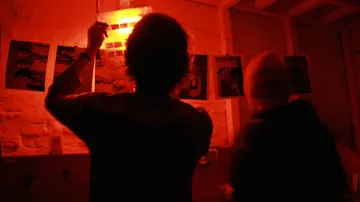 People develop photos in a red-lit darkroom.