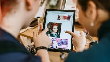 Zwei Personen schauen sich Haar-Tutorials auf dem Tablet an.